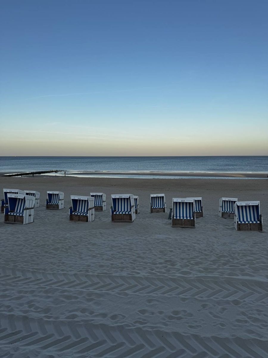 Strandkörbe in der Abenddämmerung auf Sylt, der Himmel geht von Blau in zartes Gelb über
